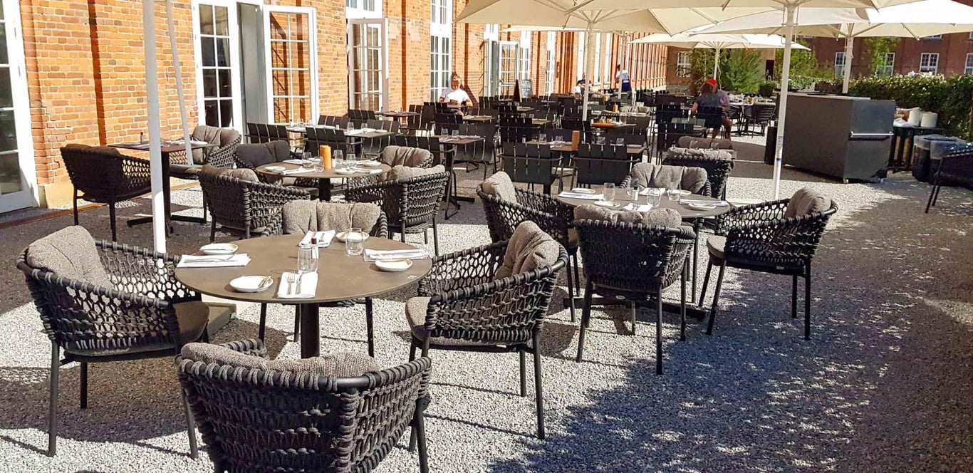 Uteplats med stabila bord och stolar under parasoller i en restaurangmiljö