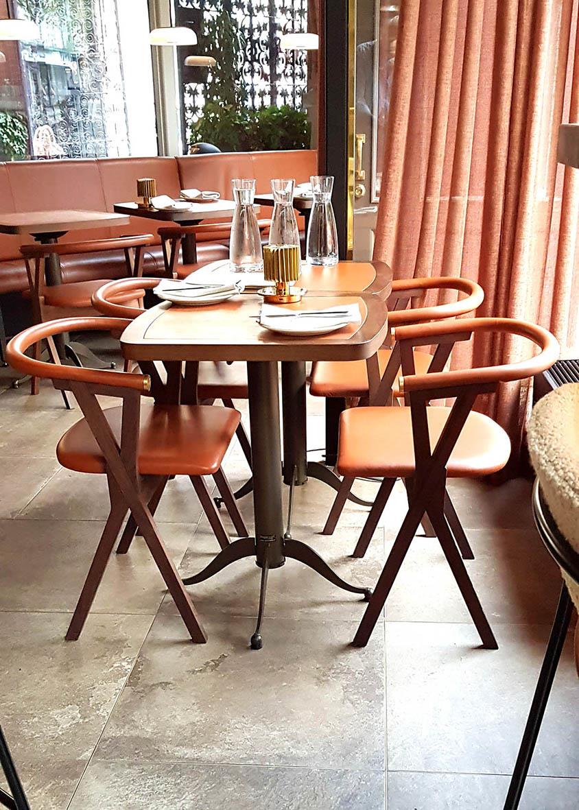 Bord med brun träskiva och fyra matchande stolar i ett inomhusmiljö med fönster och gardiner