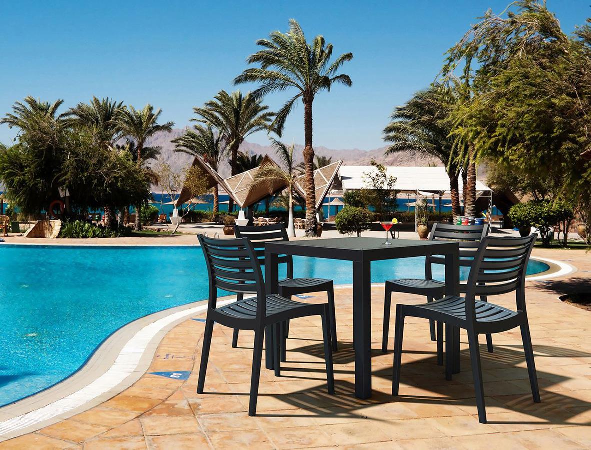 Stol Ares stapelbar svart vid pool med palmer och parasoll i bakgrunden