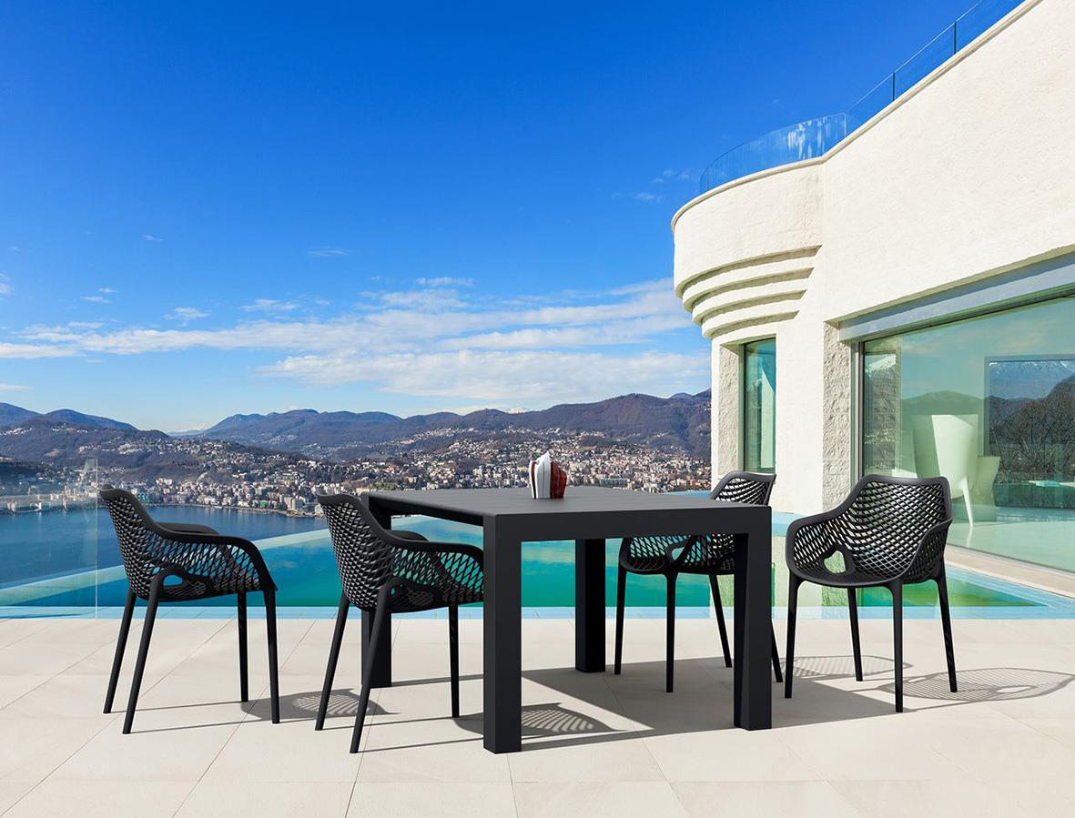 Svart stapelbar stol Air XL på terrass med utsikt över vatten och berg i bakgrunden