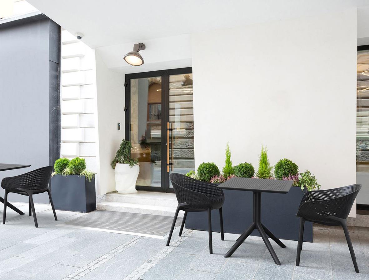 Stol Sky Pro stapelbar svart utomhus på terrass med växter och glasdörrar