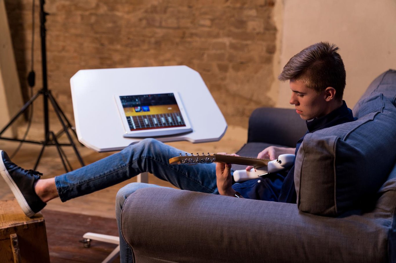 Person som ligger på en soffa och använder ett höj- och sänkbart skrivbord med en surfplatta