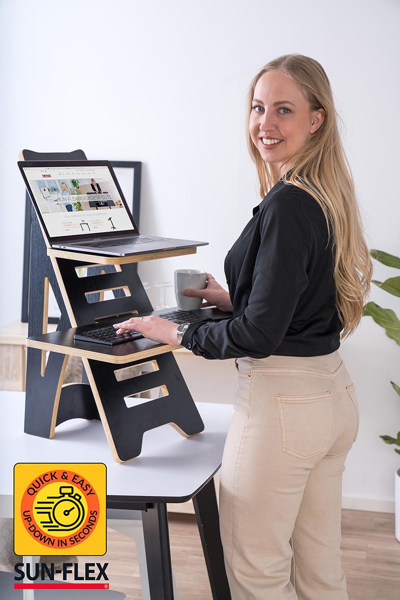 Kvinna använder portabelt ståbord Sun-Flex Easydesk Rise i svart med justerbar höjd, laptop och kopp på bordet