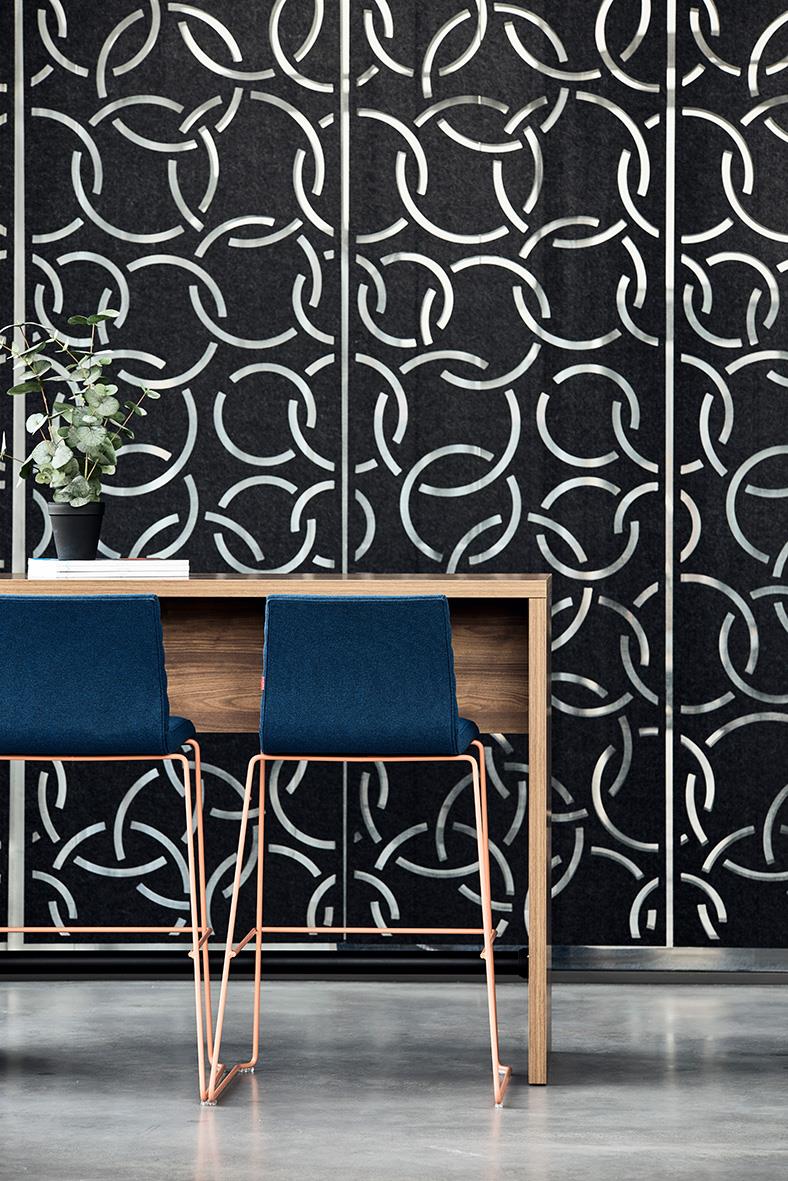 Barbord av trä med två blå stolar framför en vägg med svart och vit geometrisk mönster