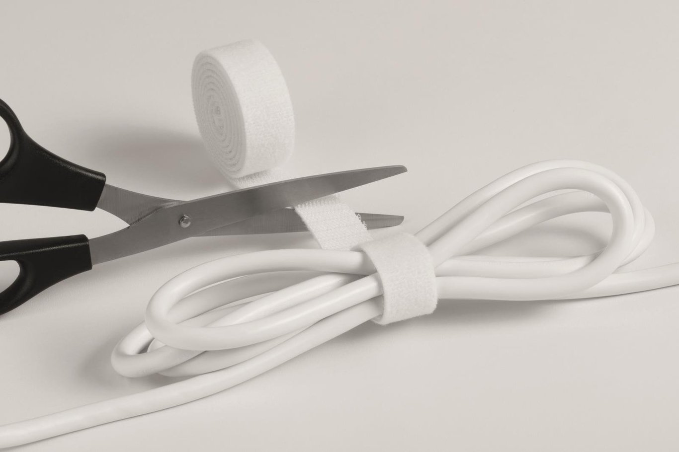Vit kabelsamlare med svart handtag, skärverktyg och kabel på en vit bakgrund