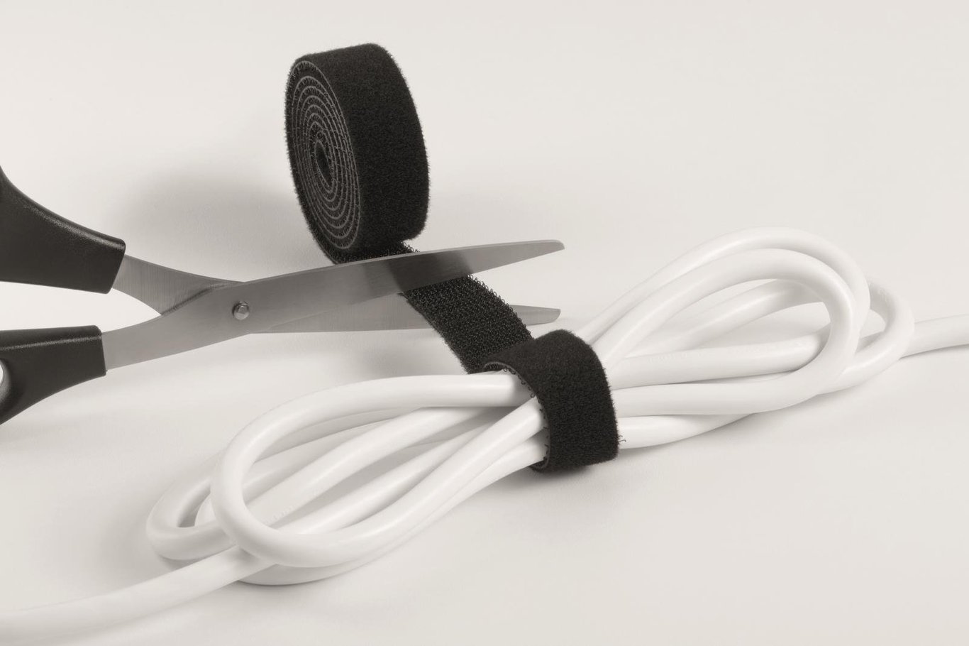 Svart kabelsamlare med 3 cm Cavoline Grip och en vit kabel fastsatt med svart kardborreband