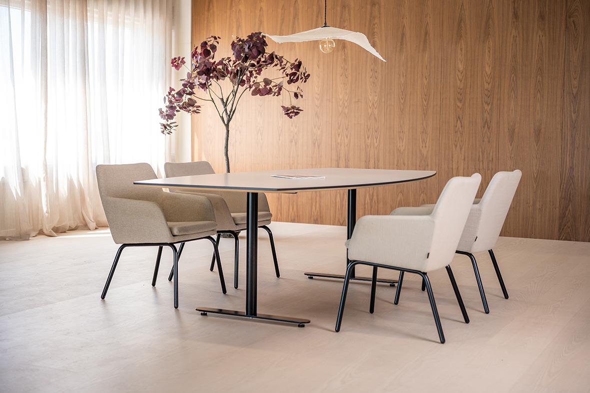 Karmstol i beige och svart med rund bord och blomma i ett modernt vardagsrum