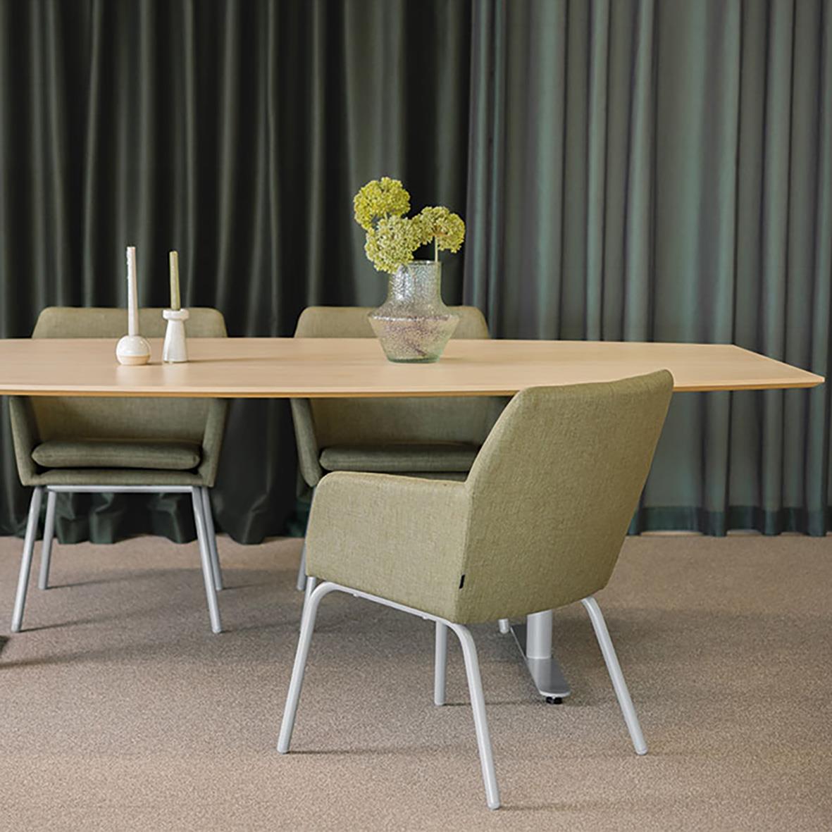 Karmstol i beige och svart med en blomvas och ljusstakar på ett bord framför mörka gardiner