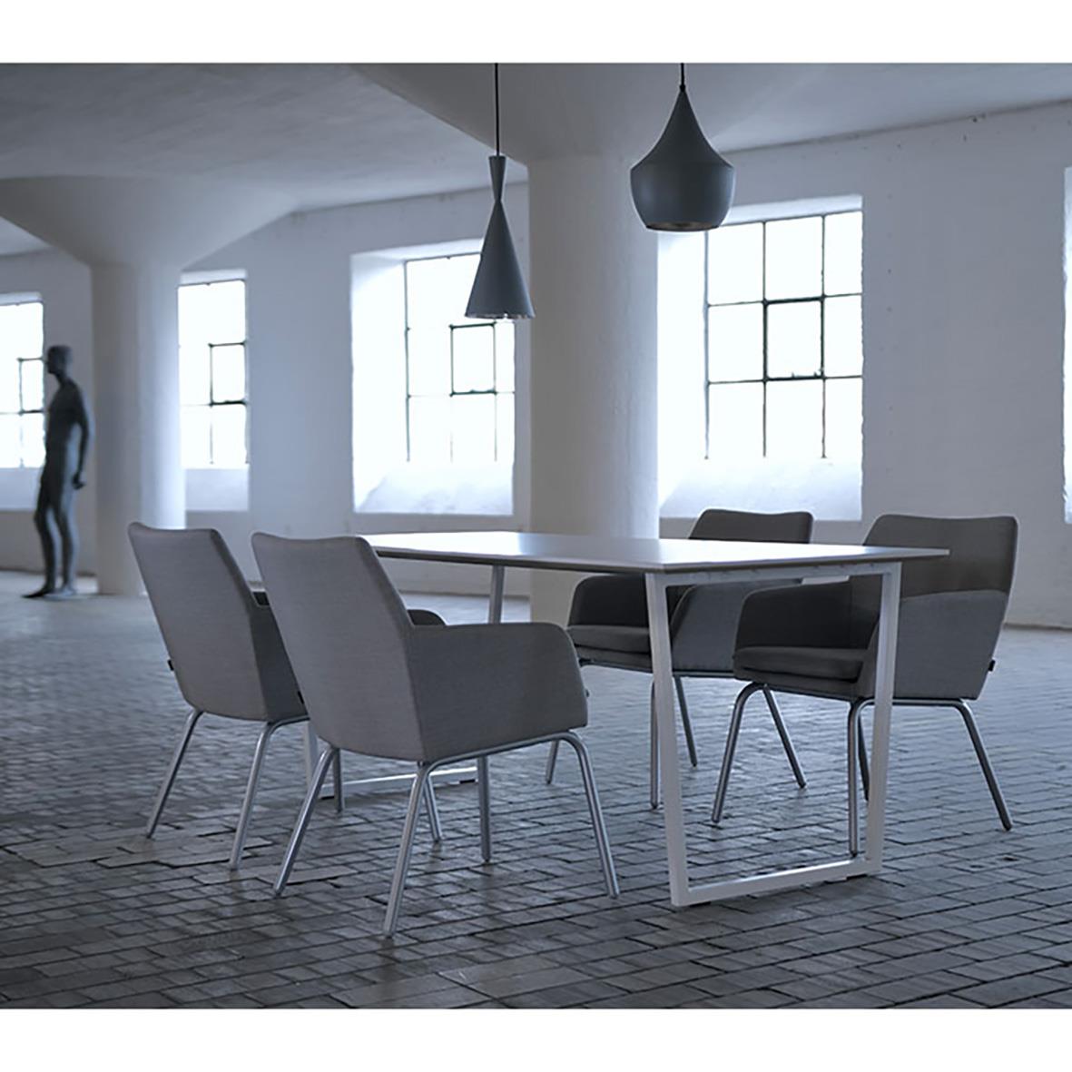 Karmstol i beige och svart runt bord i ett ljust, industriellt rum med stora fönster