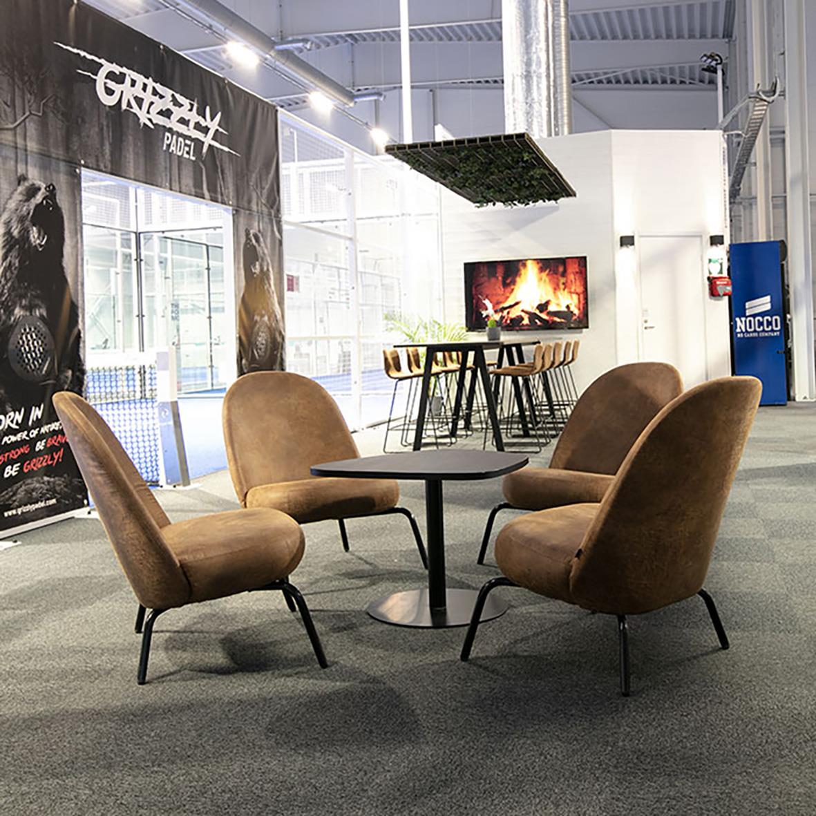 Vardagsrum eller lounge med fyra bekväma fåtöljer runt ett runt bord, modern inredning och en vägg med en braskamin och TV