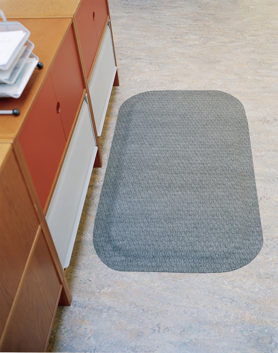 Grå arbetsplatsmatta i tyg på golvet bredvid ett skåp