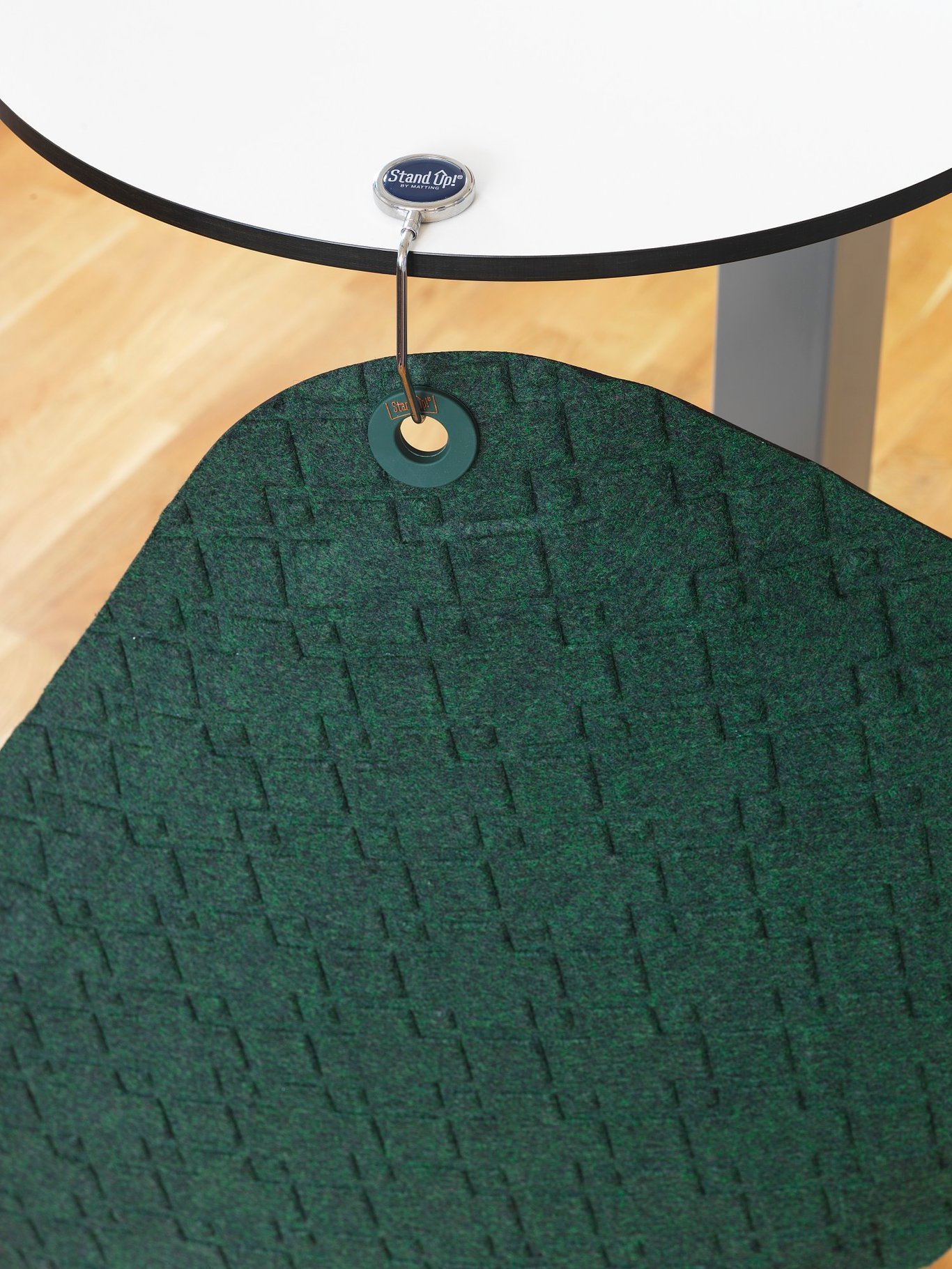 Grön matta med mönster under ett vitt bord med Stand Up-etikett