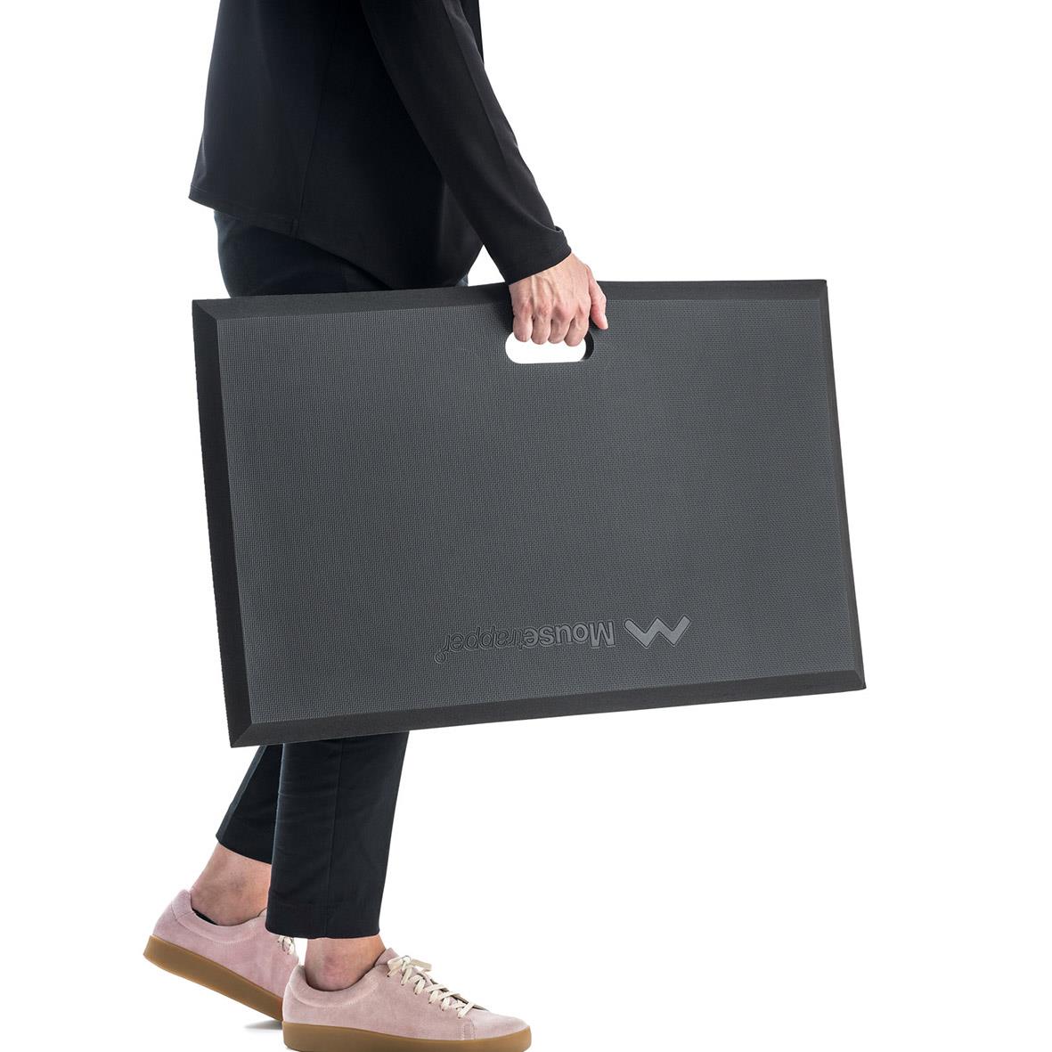 Person bär en stor svart musmatta Mousetrapper Active i handen