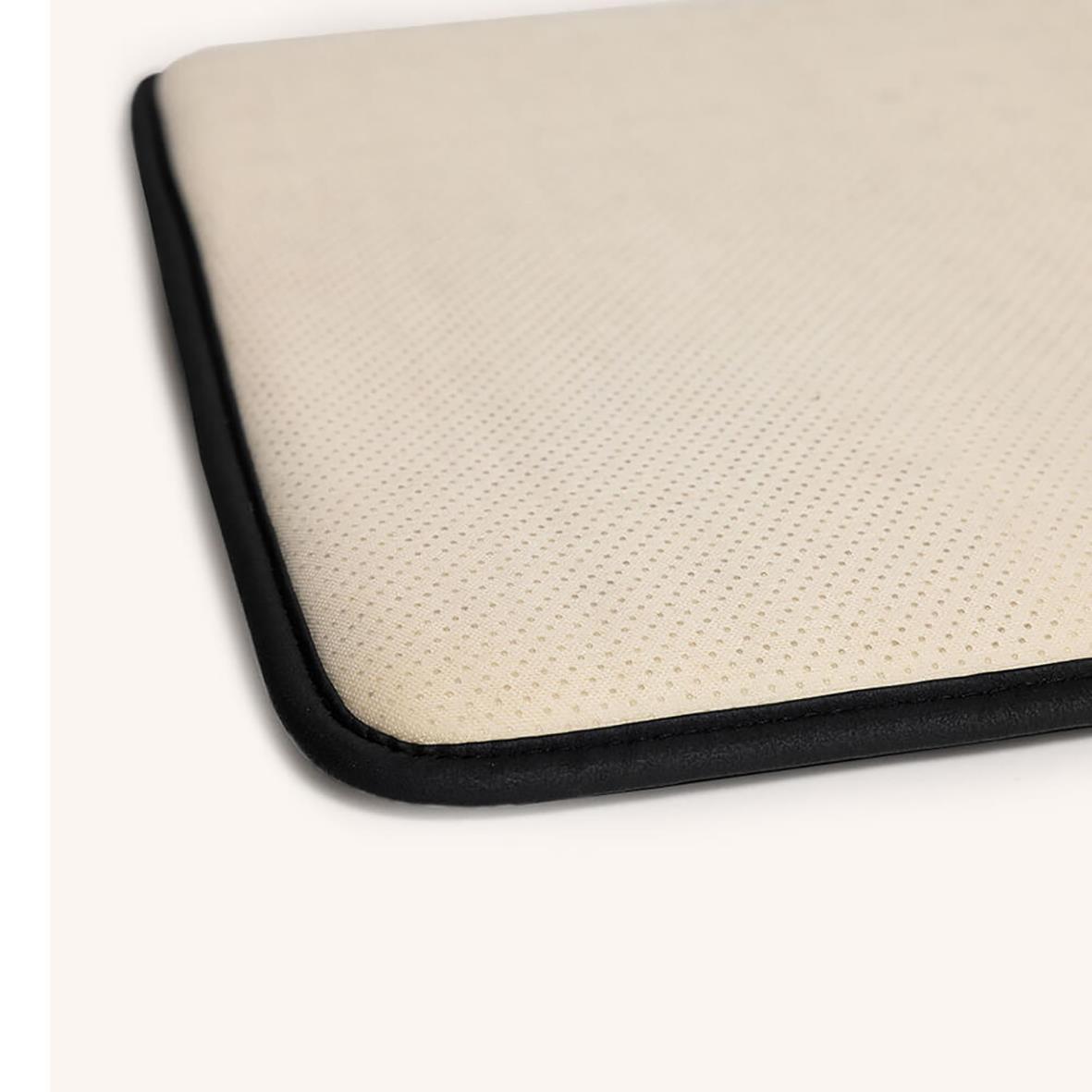 Närbild av en beige ståmatta med svart kant, designad för posturstöd och kylande funktion