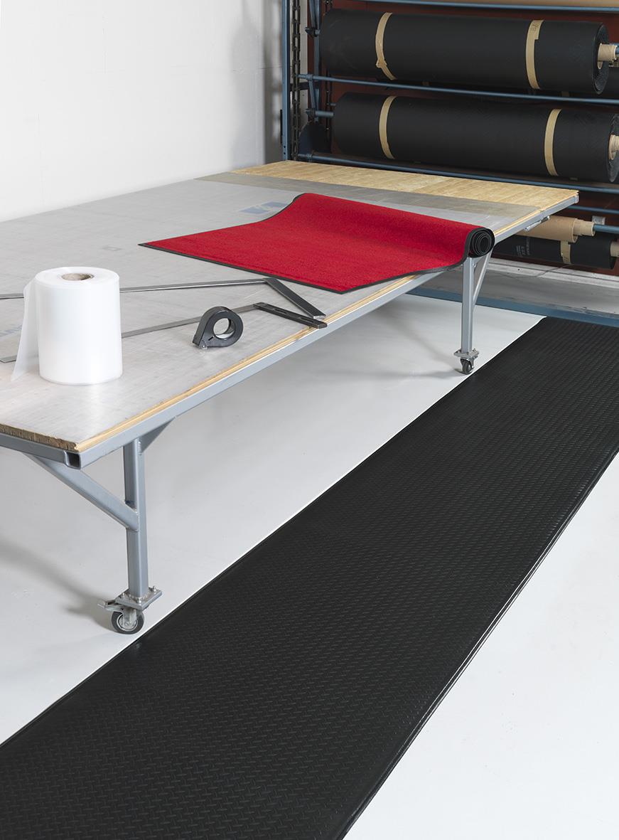 Svart arbetsplatsmatta 91x100cm på arbetsbänk med röd yogamatta och verktyg