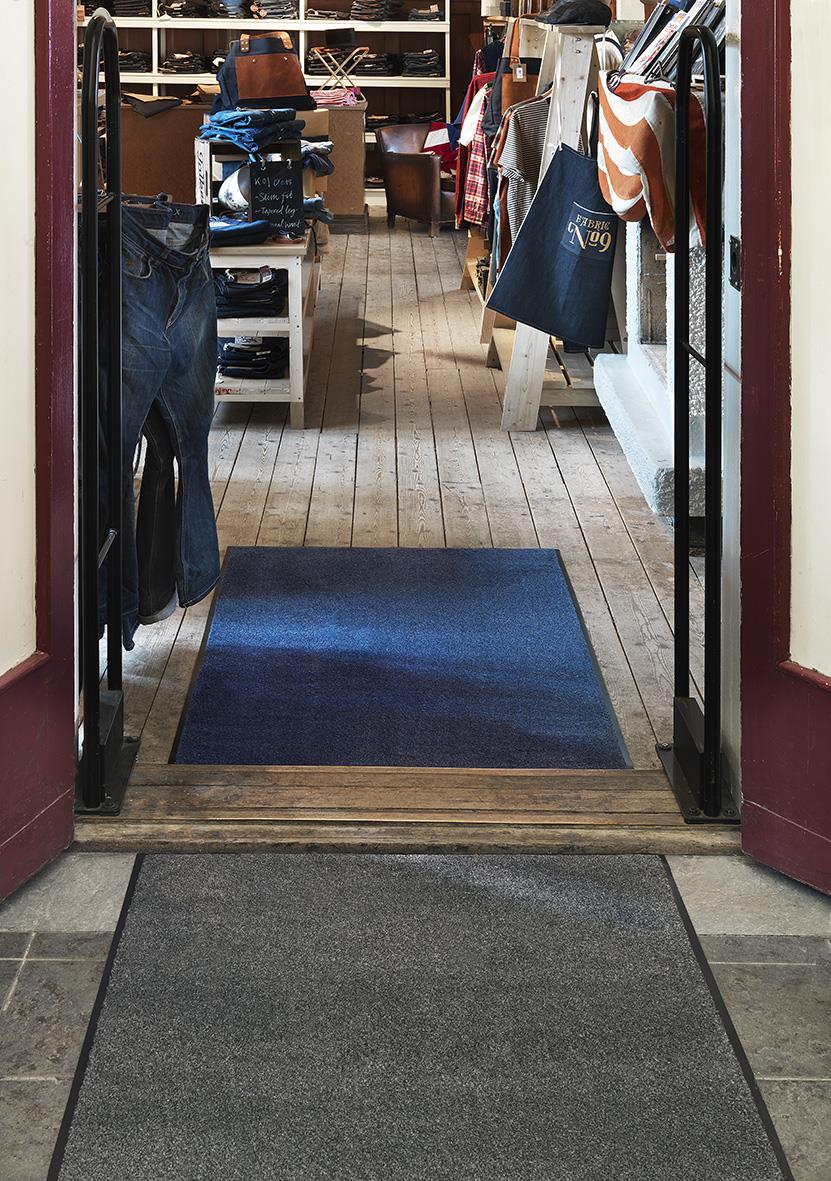 Grå torkmatta Matting Solett 80x60cm placerad vid ingången till en butik