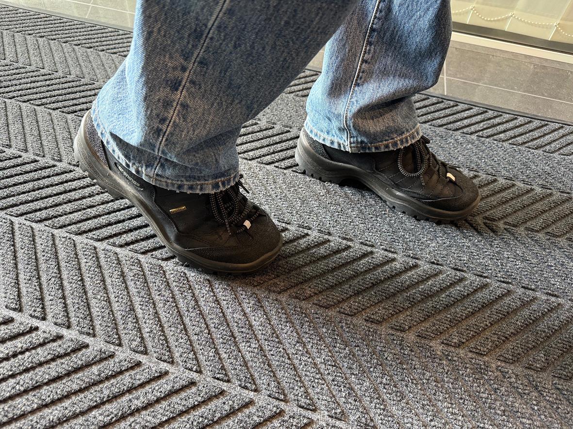 Person står på grå entrématta Activa Combi Action 90x150cm, klädd i jeans och sneakers