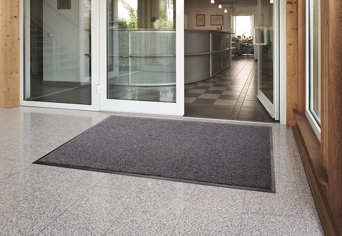 Entrématta Activa Pro Nitril Granit 115x200cm utanför ingången på en grå klinker- och betonggolv