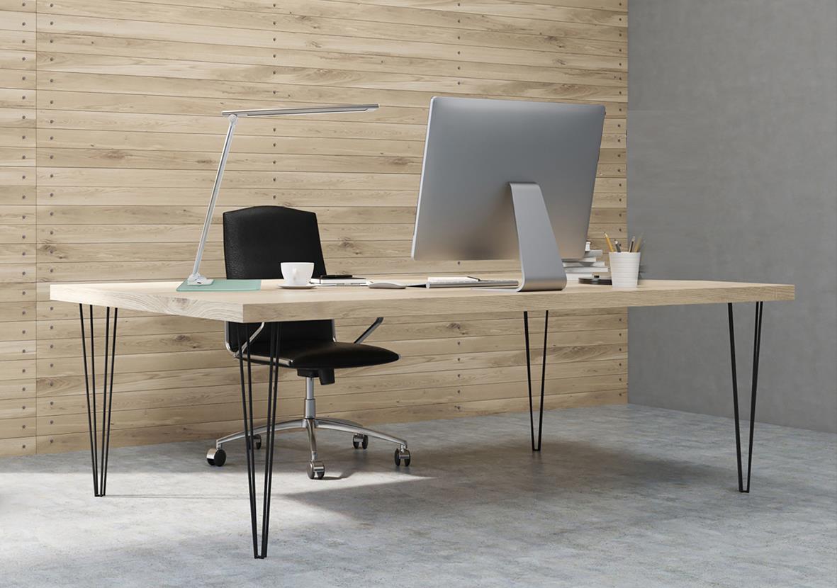 Kontorsbord med svart kontorsstol, dator och skrivbordslampa i ett modernt kontorsutrymme