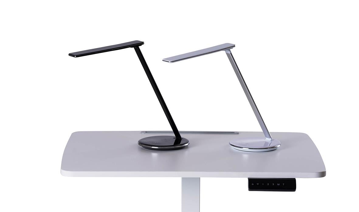 Två moderna bordslampor, en svart och en vit, placerade på ett vitt skrivbord