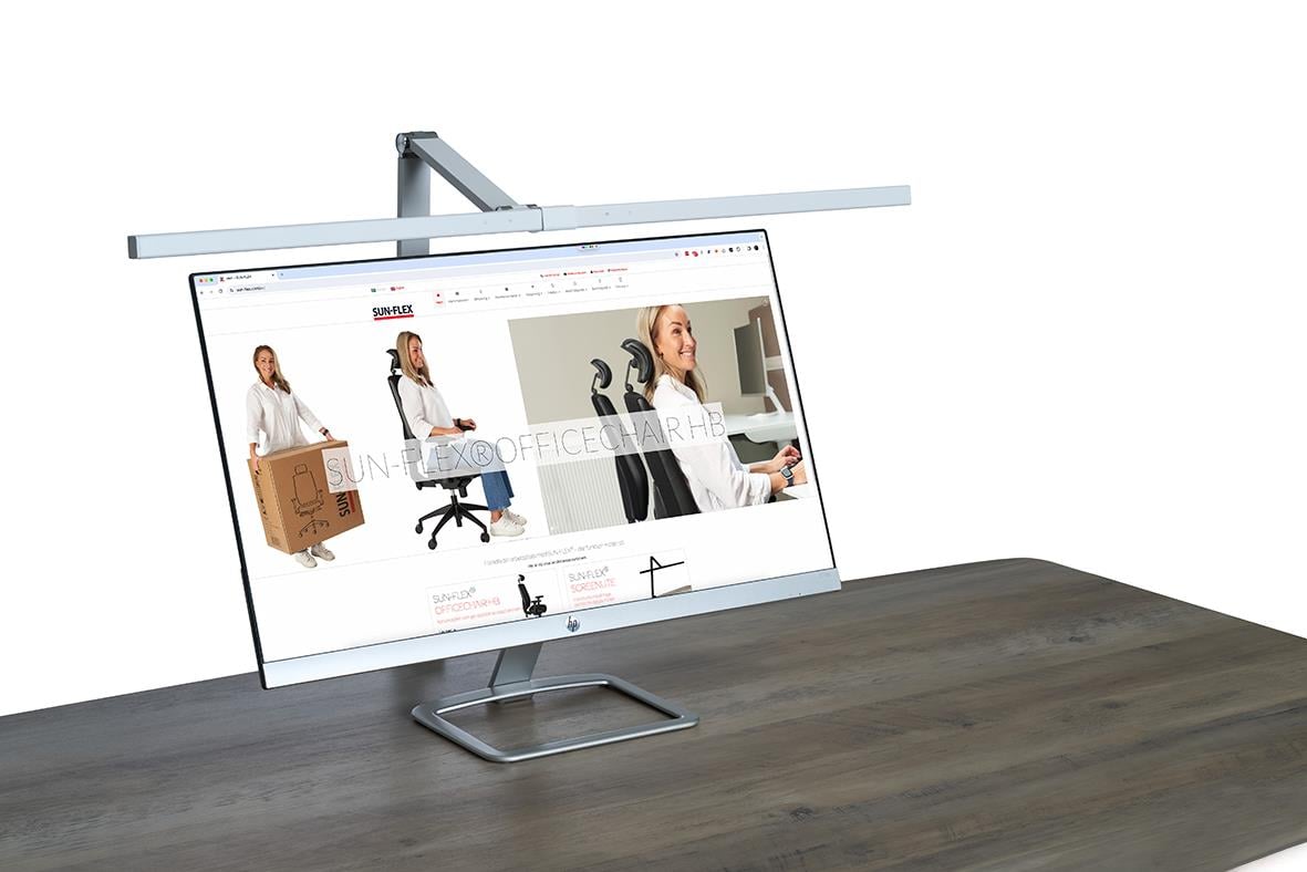 Bordslampa Sun-Flex Screenlite Vit ovanför en datorskärm på ett skrivbord