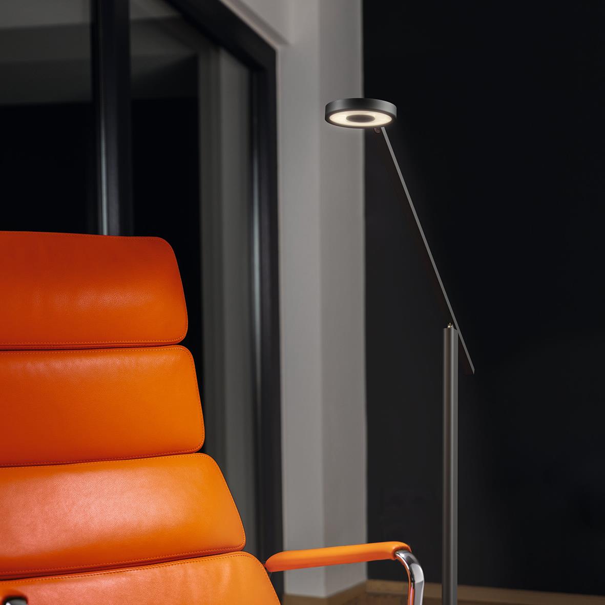 Svart golvlampa Luctra Floor Lite bredvid orange stol i modern inredning