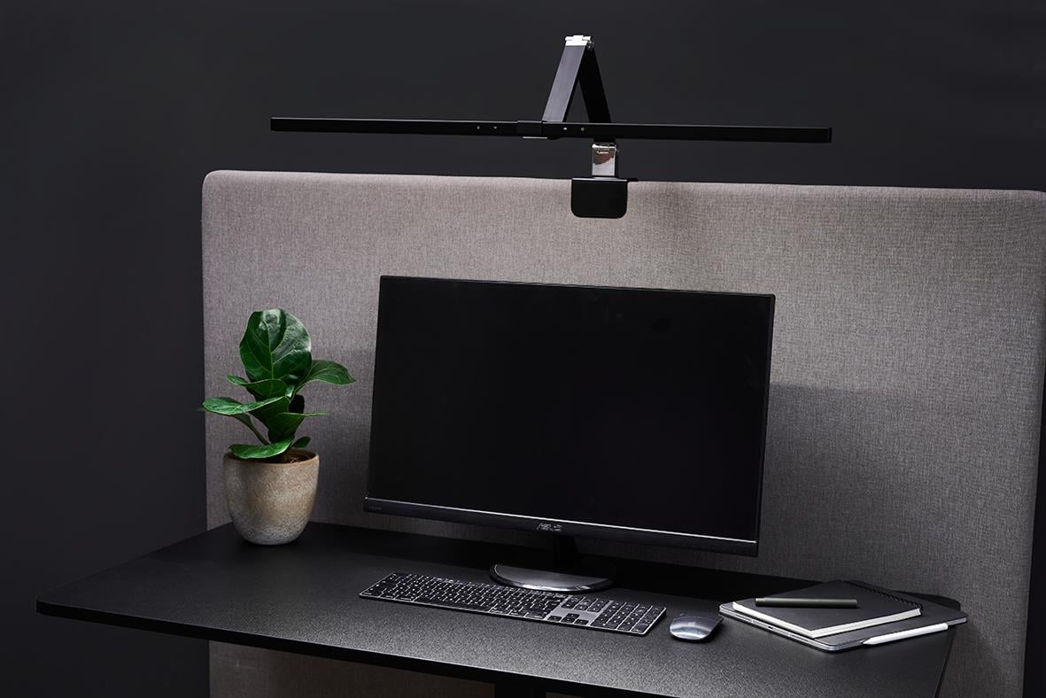 Bordslampa Sun-Flex Screenlite Panel svart ovanför skrivbord med dator och växt