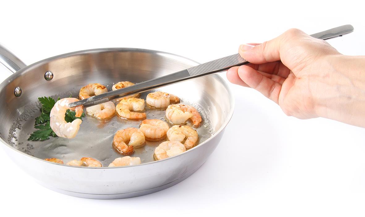 Person steker räkor i en stekpanna med en metallspatel