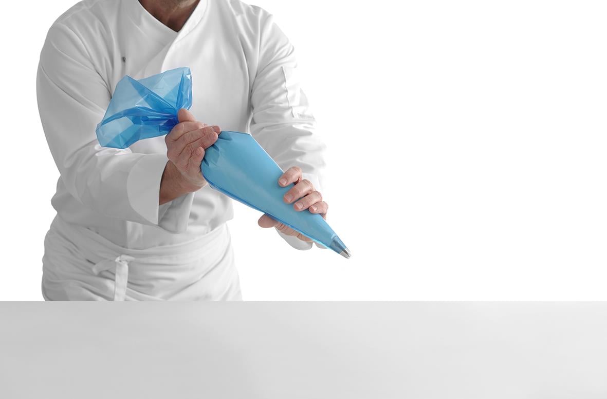 Person som fyller ett blått bakverk med en spruta