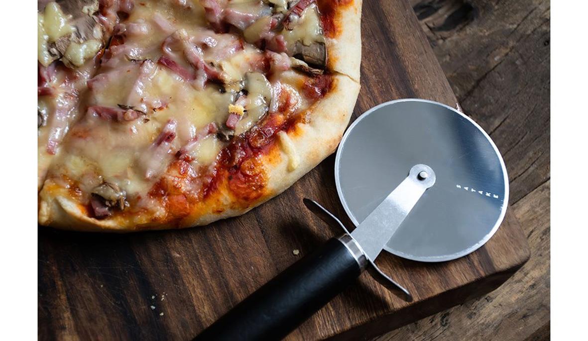 Pizza och pizzaskärare på träbord
