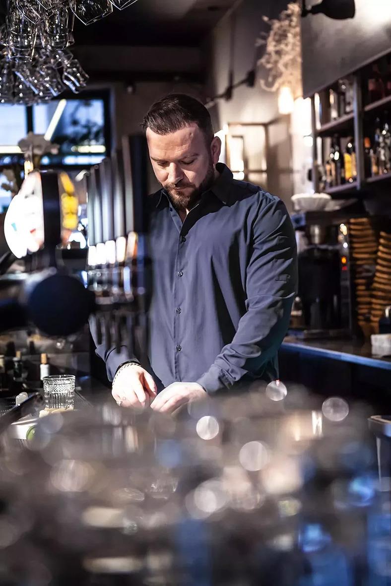 Man i marinblå kockskjorta i kök eller barmiljö, fokuserad på arbete