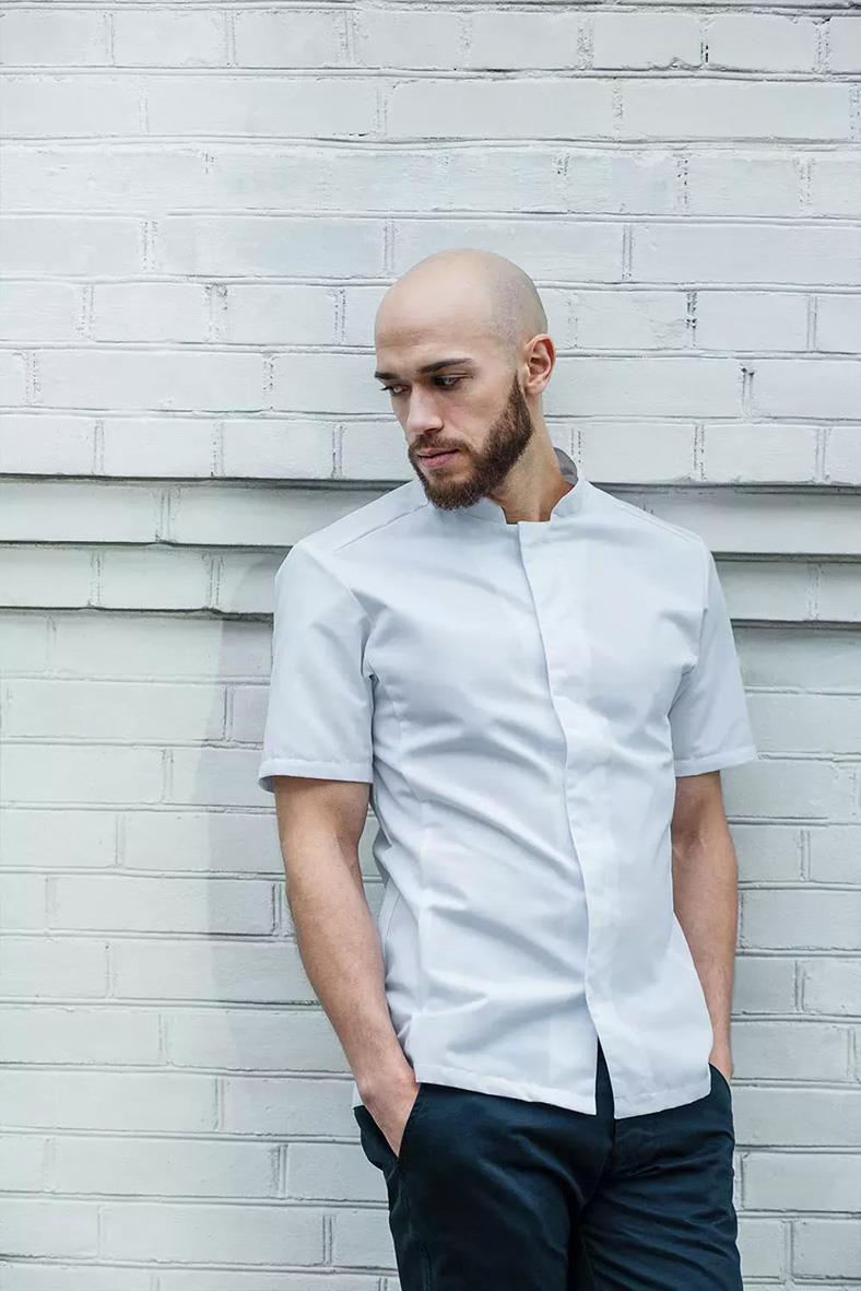 Man i vit kockskjorta med korta ärmar står framför vit vägg