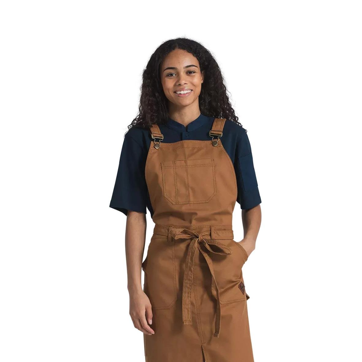 Ung kvinna i snickarförkläde Segers 4092 Nougat 72x98cm, mörkblå tröja, leende