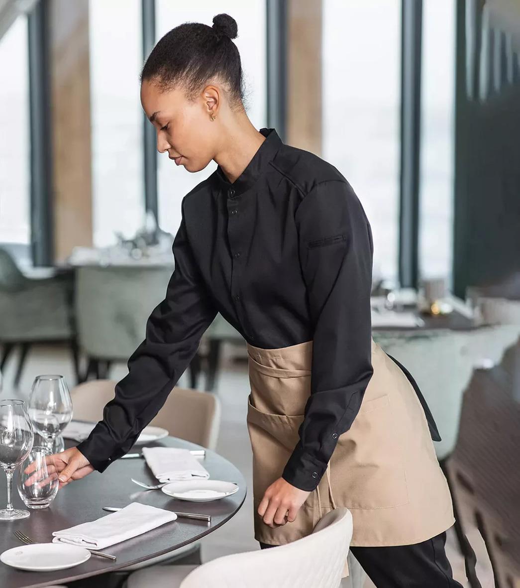 Kvinna i svart förkläde som serverar vid ett bord i ett modernt restaurangmiljö