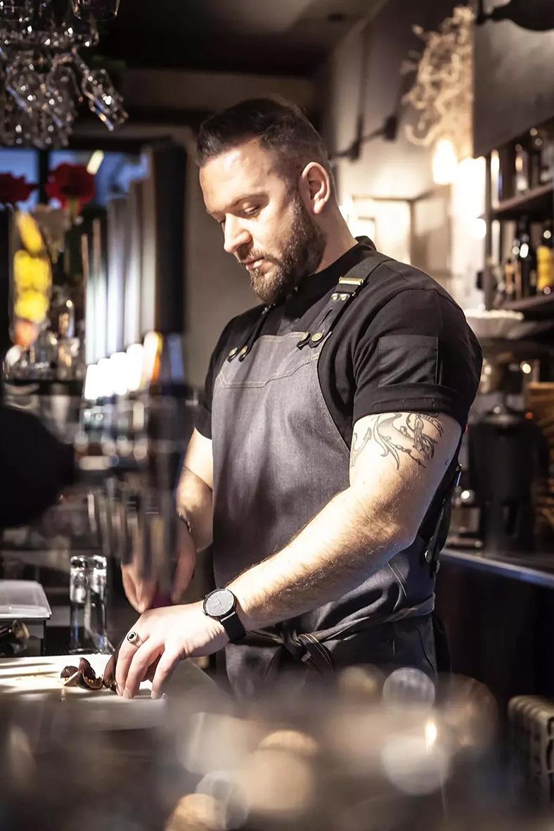 Man i svart och grå kockkläder i kök, fokuserad på arbete