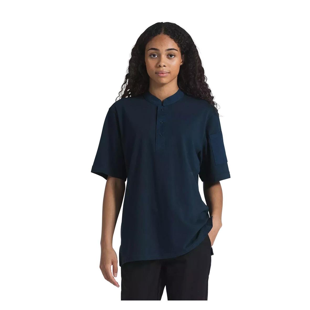 Ung kvinna i mörk marin unisex kockpiké med korta ärmar och ståkrage