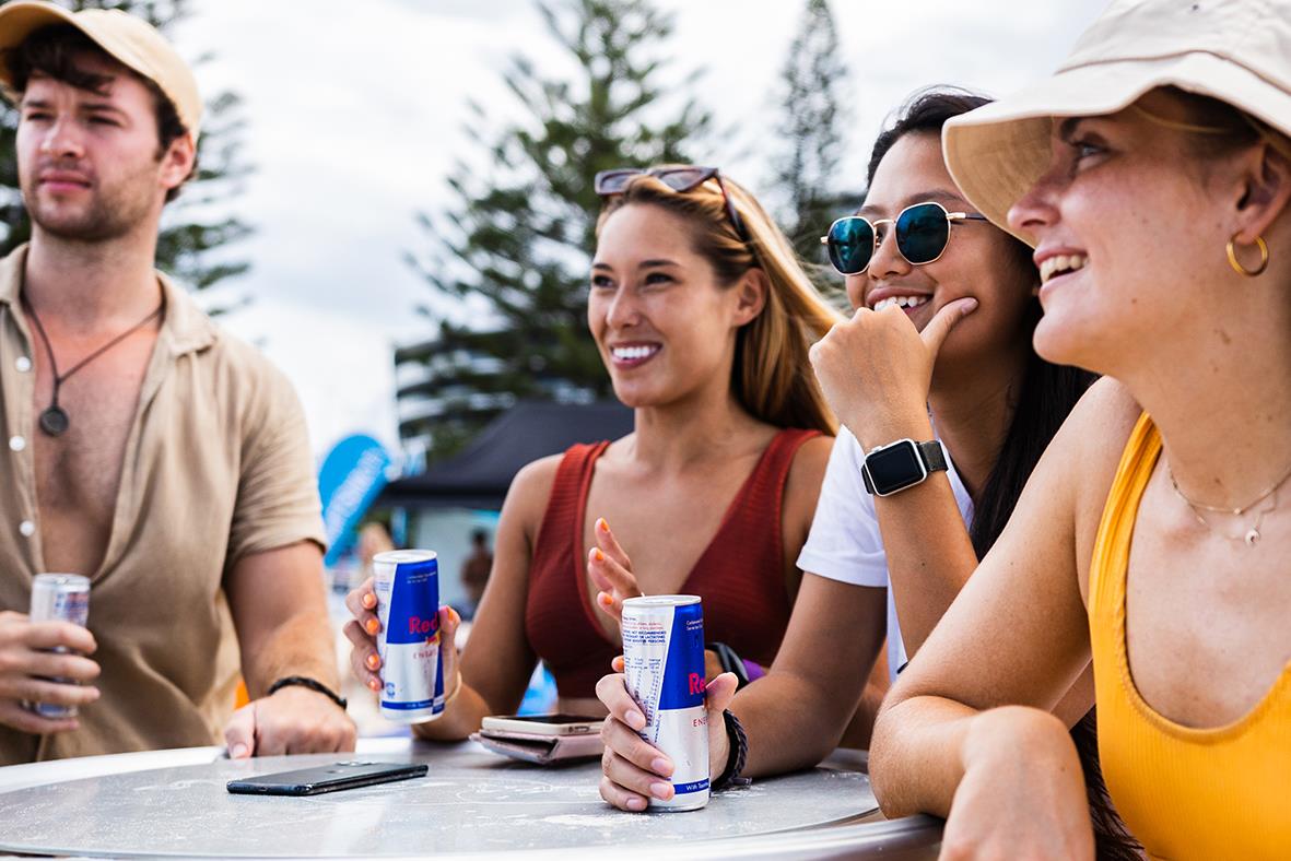 Grupp unga vuxna utomhus som dricker energidryck Red Bull 25cl inklusive pant