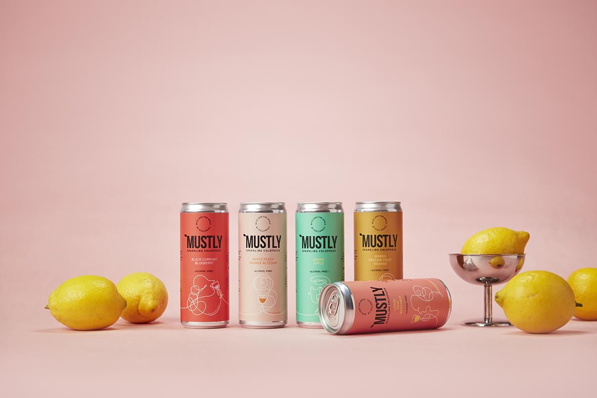 Fyra burkar Mustly blåbärsdryck 33cl med citroner och en skål med citroner mot rosa bakgrund