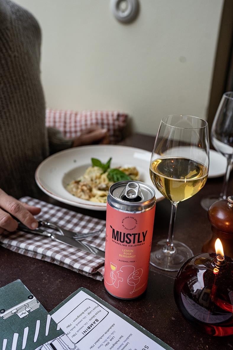 Dryck Mustly Lemon Rose 33cl i burk med glas vitt vin på bordet