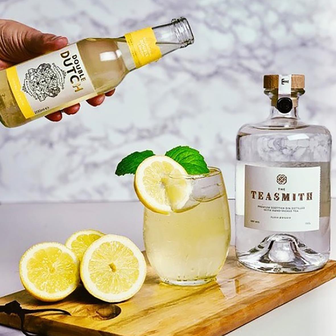 Lemonad med citron och mynta i glas, bakgrund av en flaska tonic och lemon i bakgrunden