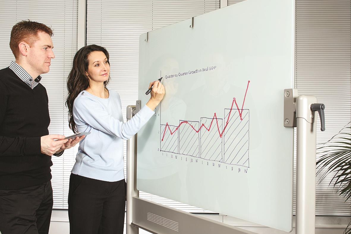 " personer framför en vit magnetisk glastavla med diagram och text, en skriver på tavlan"