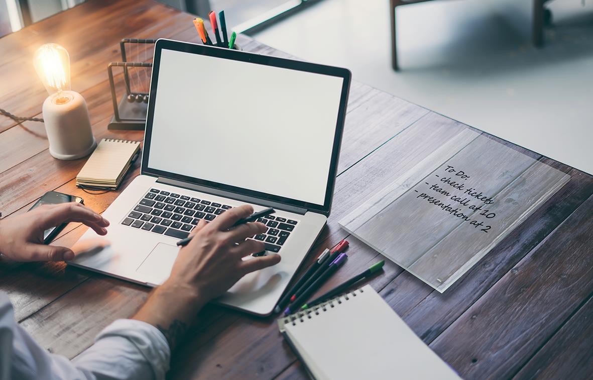 Person använder en transparent A4 whiteboardtavla Nobo Mini på ett skrivbord med pennor och anteckningar