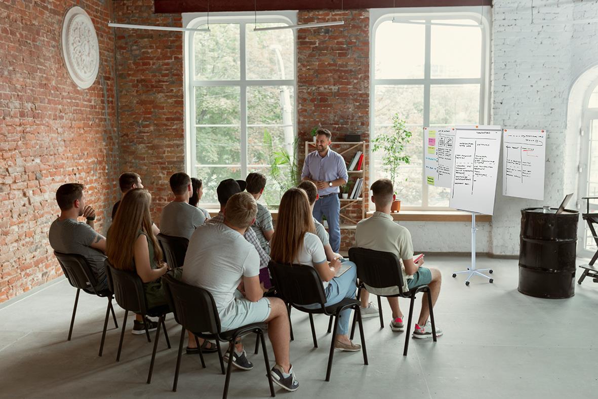 Grupp människor i ett mötesrum med blädderblocksställ Nobo Classic, presenterar inför en grupp