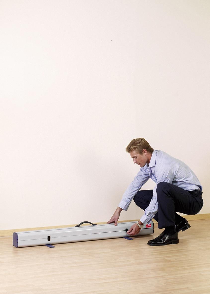 Man placerar en bärbar projektorduk på golvet i ett tomt rum