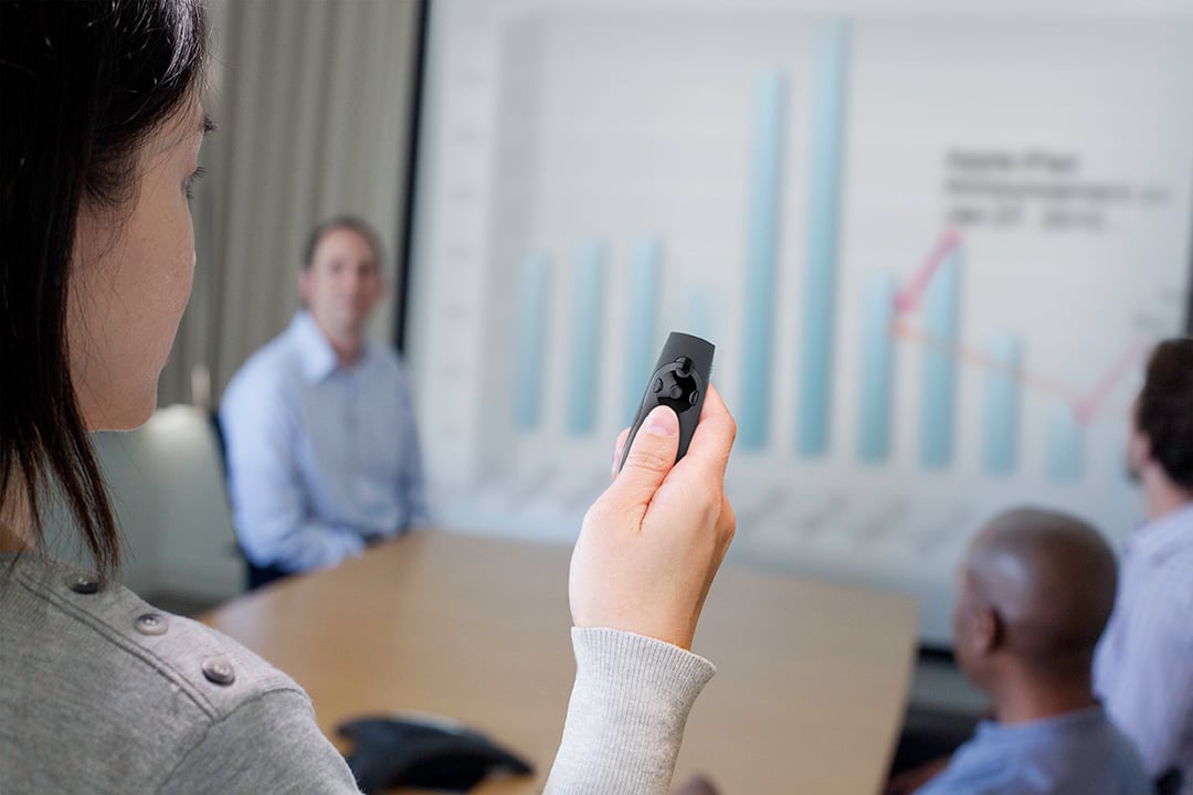 Person som håller en grön laserpekare under en presentation med diagram på skärmen