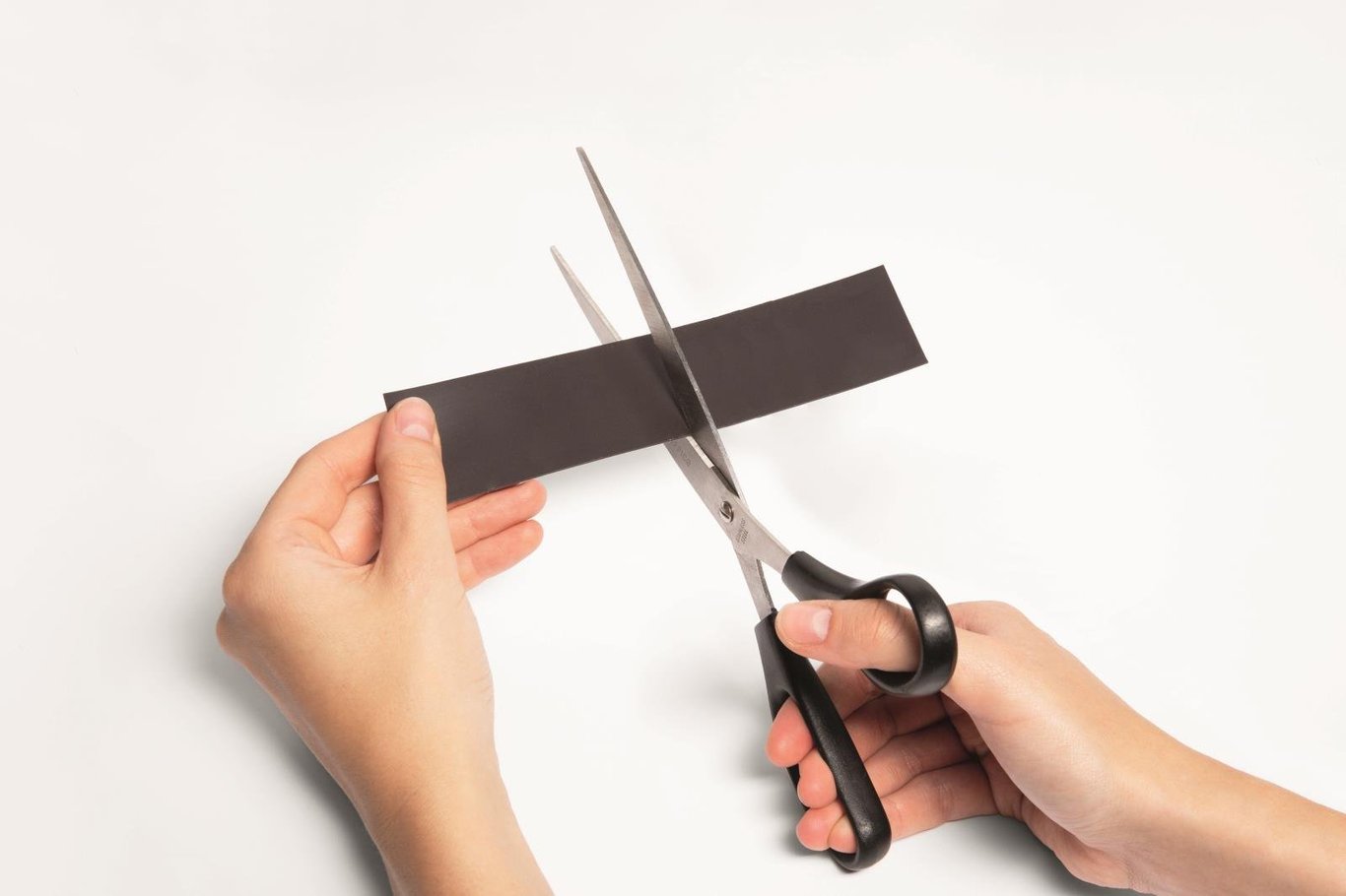 Person klipper ett svart magnetband med sax