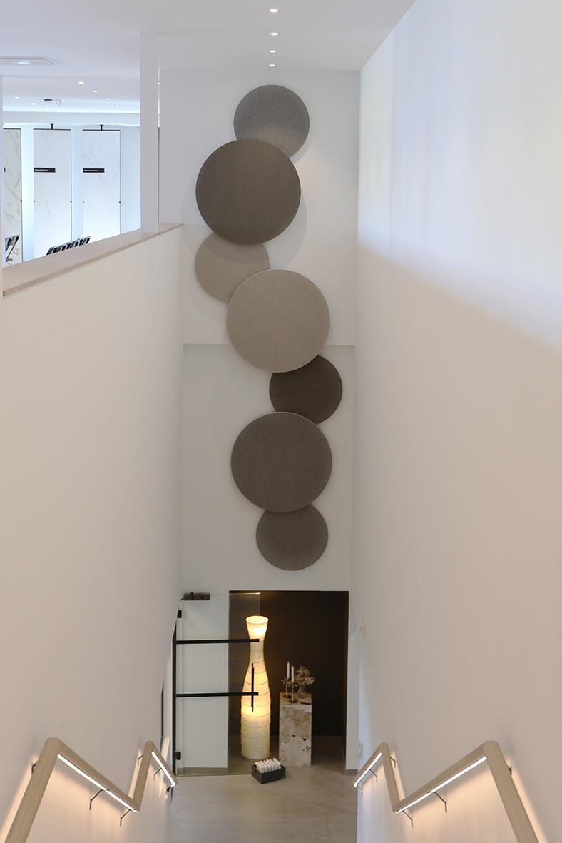 Ljudabsorberande väggdekoration med cirklar i olika nyanser av vitt och grått på en vit vägg i ett inomhusmiljö