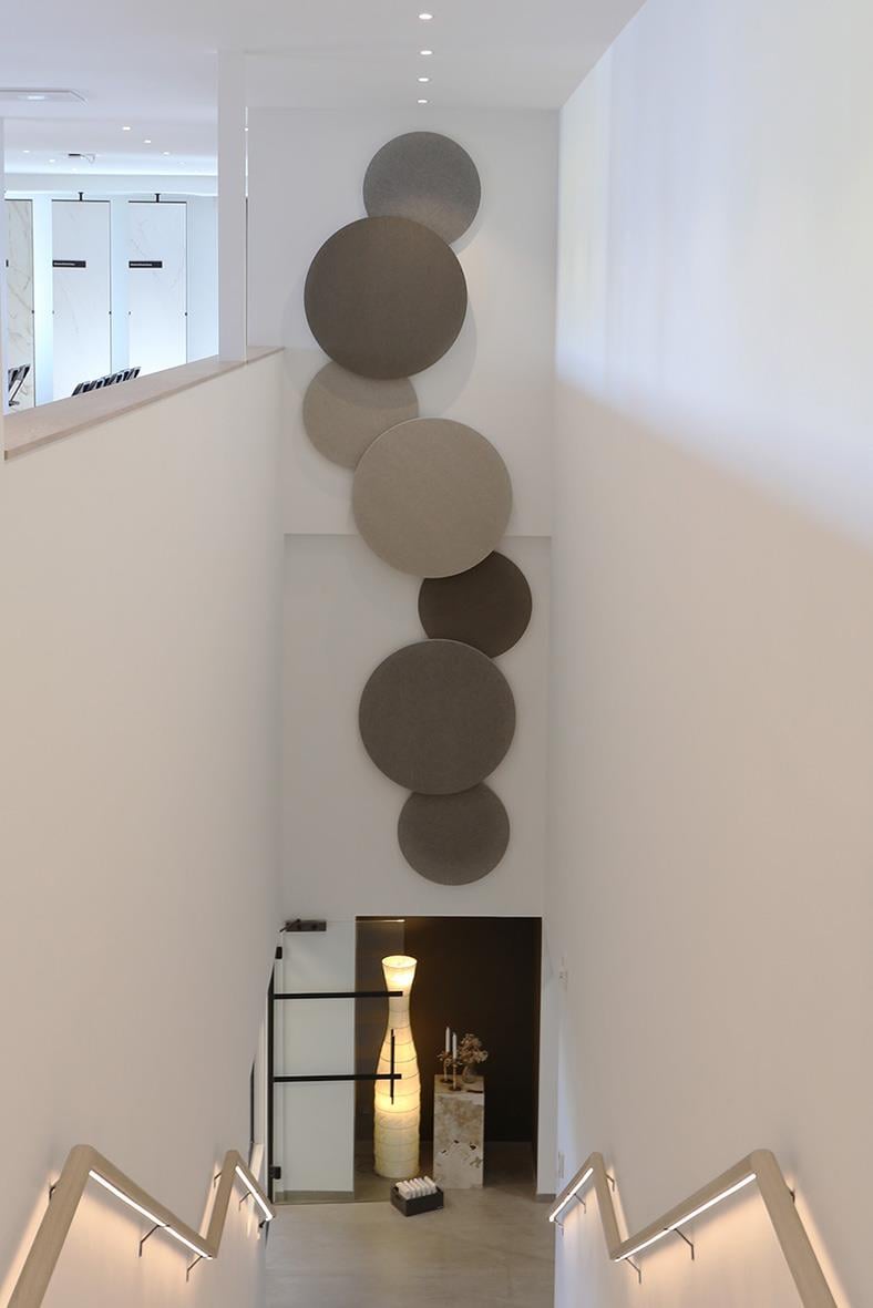 Ljudabsorberande väggdekoration med cirklar i olika nyanser av vitt och grått på en vit vägg i ett inomhusmiljö