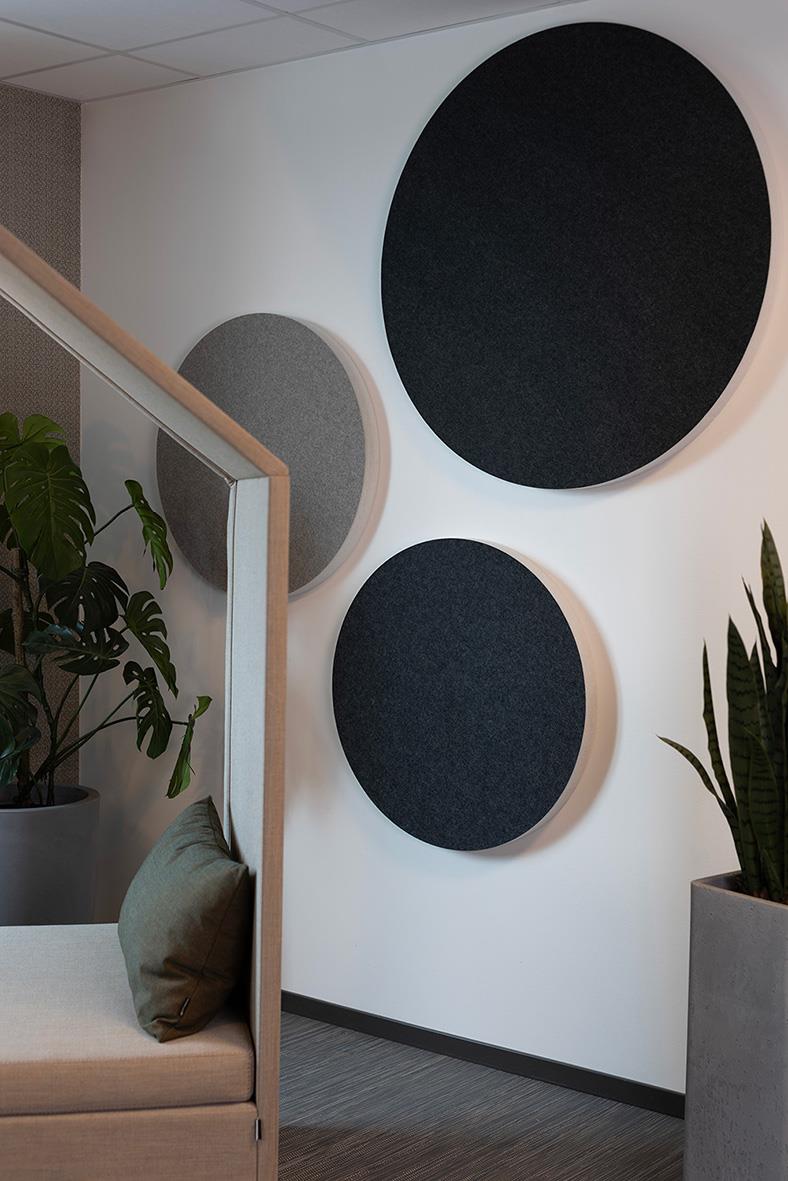 Tre ljudabsorberande väggpaneler i olika storlekar och färger, monterade på vit vägg i inomhusmiljö