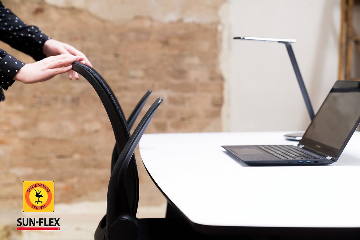 Person som justerar en svart kontorsstol vid ett skrivbord med en laptop